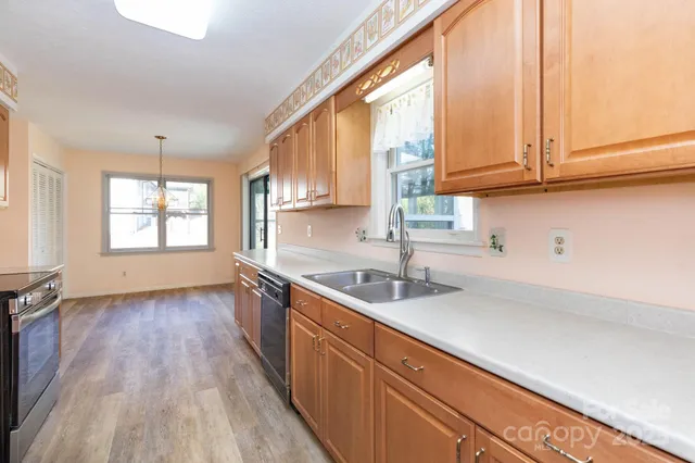 a kitchen with granite countertop stainless steel appliances a sink window and cabinets