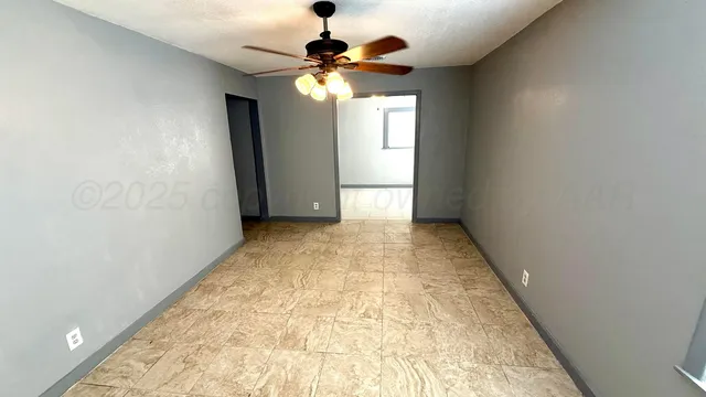en empty room with window and chandelier fan