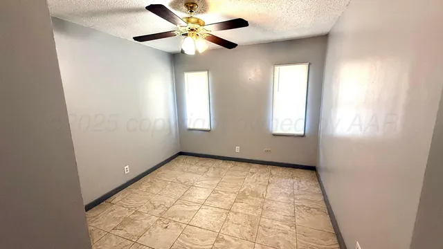 an empty room with windows and fan