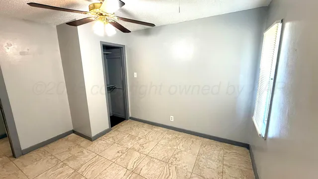 an empty room with windows and fan