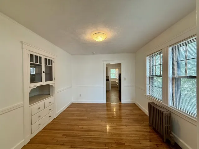 a view of an empty room with window and wooden floor