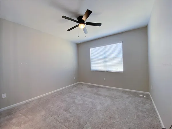 an empty room with ceiling fan and window