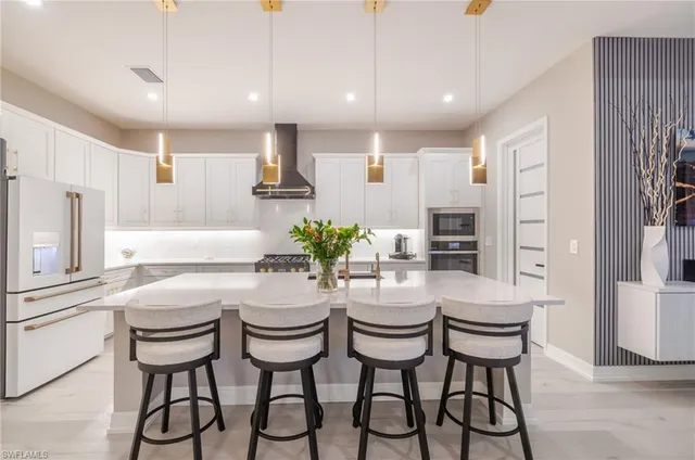 a kitchen with stainless steel appliances kitchen island granite countertop a kitchen island and chairs in it
