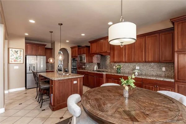 a kitchen with stainless steel appliances granite countertop a sink a stove a refrigerator and island