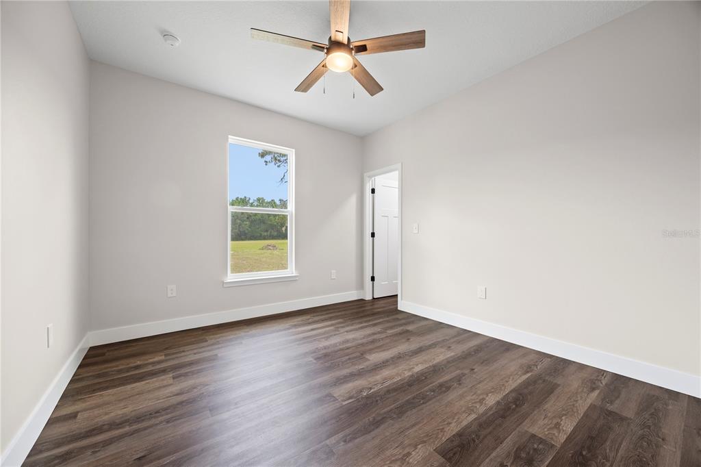 151 Southwest Scott Place Lake City, FL 32024 - Photo 27 of 47 an empty room with wooden floor chandelier fan and windows