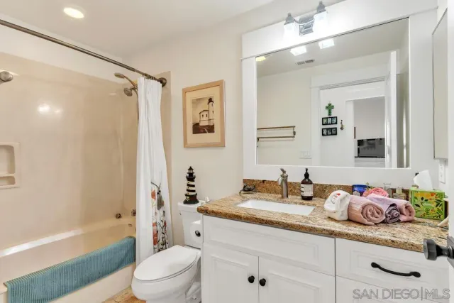 a bathroom with a granite countertop sink a toilet and shower