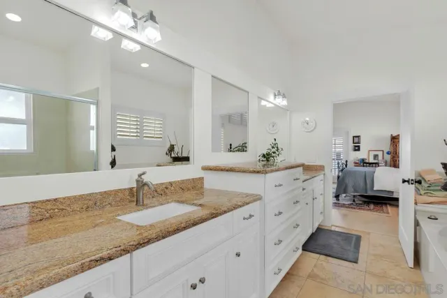 a bathroom with double vanity sinks a vanity a lamp and a mirror