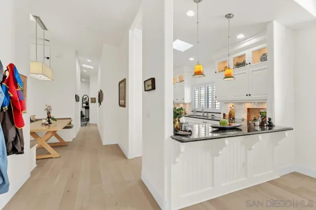 a very nice looking dining room with kitchen island white cabinets and a chandelier
