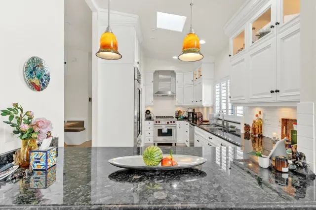 a kitchen with stainless steel appliances granite countertop a sink a stove a dining table and chairs