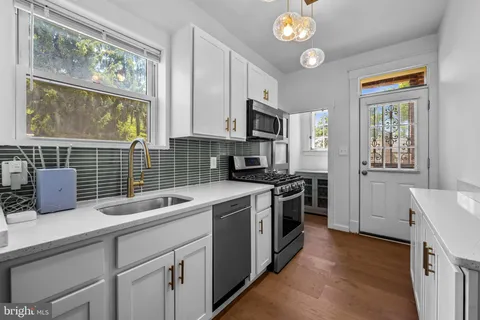 a kitchen with stainless steel appliances cabinets and wooden floor