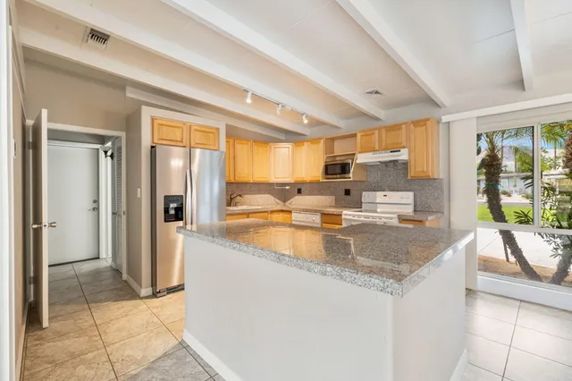 a kitchen with stainless steel appliances granite countertop a sink and a refrigerator