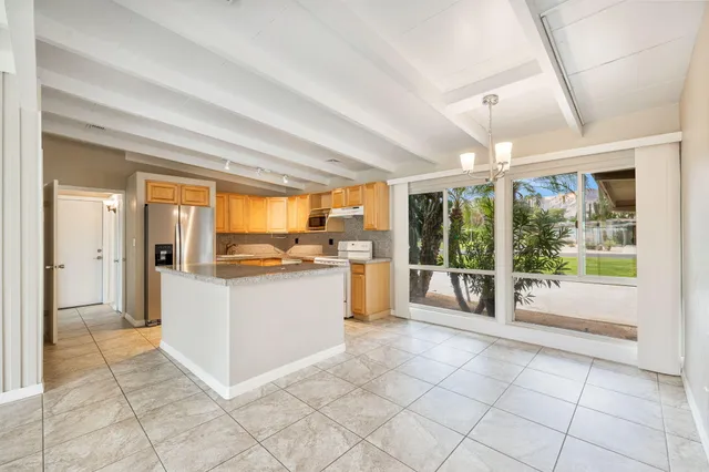 a large white kitchen with a large window and kitchen view