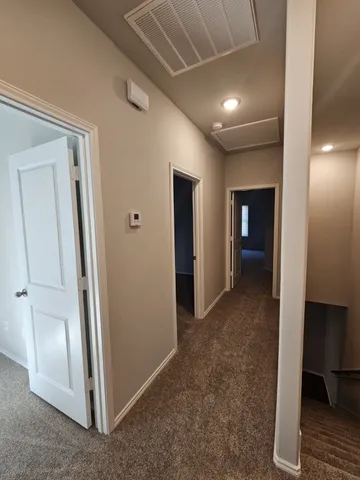 a view of a hallway with an empty room and a bathroom