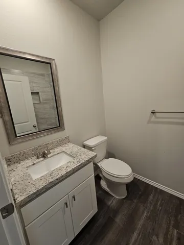 a bathroom with a granite countertop toilet and sink