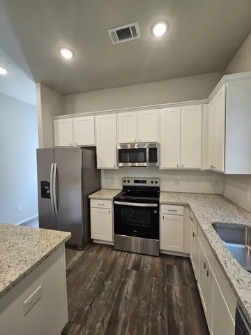 a kitchen with granite countertop a refrigerator stove and sink