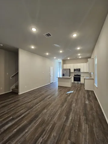 a view of kitchen with kitchen island wooden floors appliances and cabinets