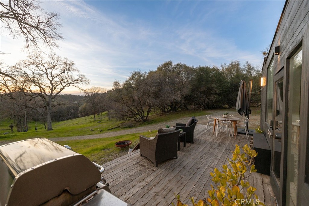33940 Jennifer Way Coarsegold, CA 93614 - Photo 62 of 75 a view of a patio with couches table and chairs under an umbrella with wooden floor and fence