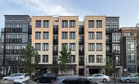 a front view of a building with lot of cars and trees