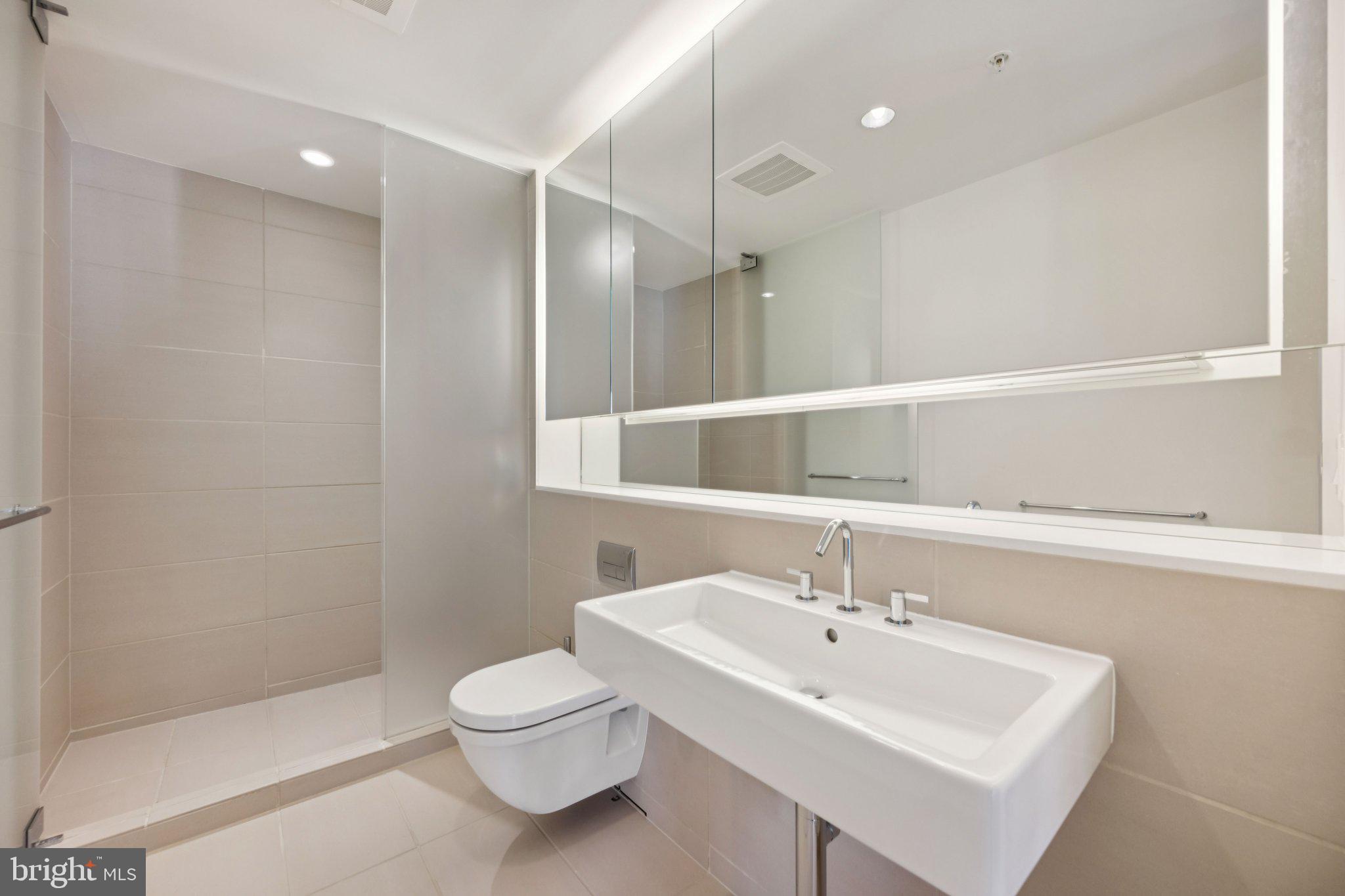 925 H Street Northwest, Unit 903 Washington, DC 20001 - Photo 13 of 36 a bathroom with a sink a toilet and a mirror