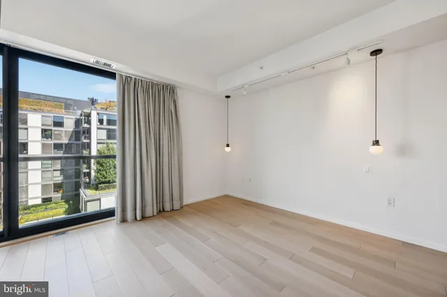 a view of an empty room with wooden floor and a window