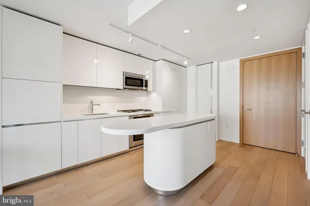a kitchen with stainless steel appliances white cabinets and wooden floor