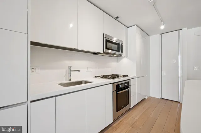 a kitchen with stainless steel appliances granite countertop a sink a stove a microwave and wooden cabinets