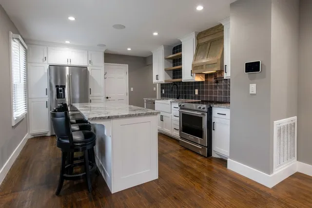 a kitchen with kitchen island granite countertop a stove and a refrigerator