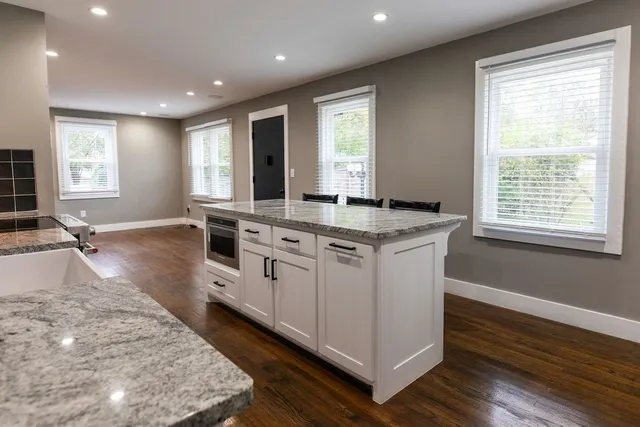 a view of a kitchen counter top space with stainless steel appliances granite countertop wooden floor and a window