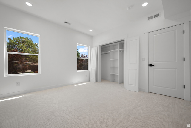 7238 South 525 East Midvale, UT 84047 - Photo 19 of 29 Light-toned carpeting in a room featuring two windows with exterior views, recessed ceiling lighting, and a built-in closet system with shelving and hanging rods