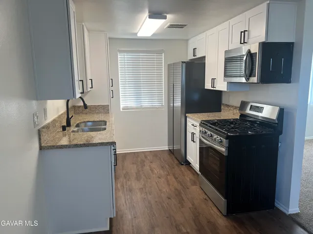 a kitchen with stainless steel appliances granite countertop a stove a sink and a refrigerator
