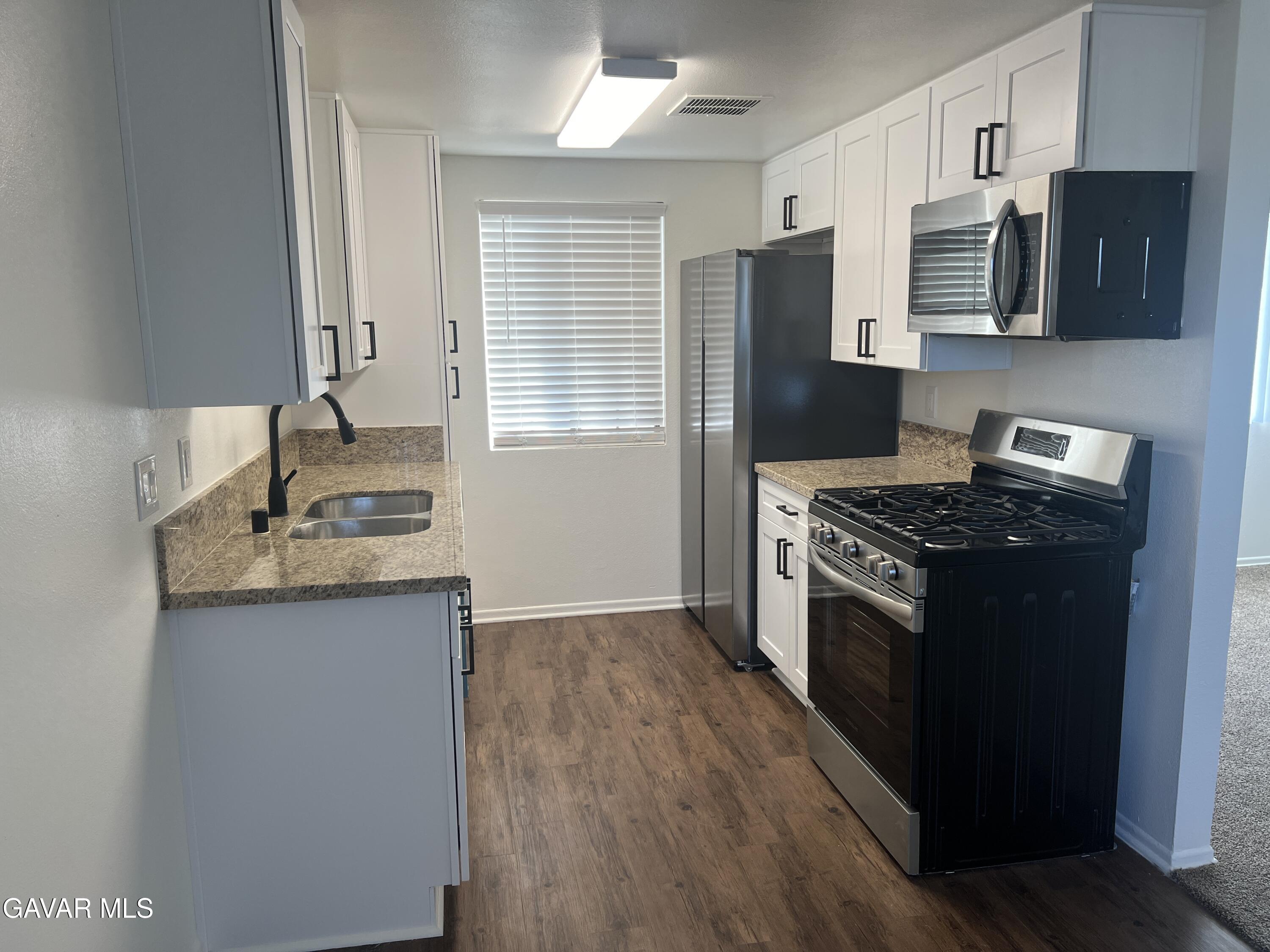 4202 West Ave L, Unit 7 Quartz Hill, CA 93536 - Photo 2 of 14 a kitchen with stainless steel appliances granite countertop a stove a sink and a refrigerator