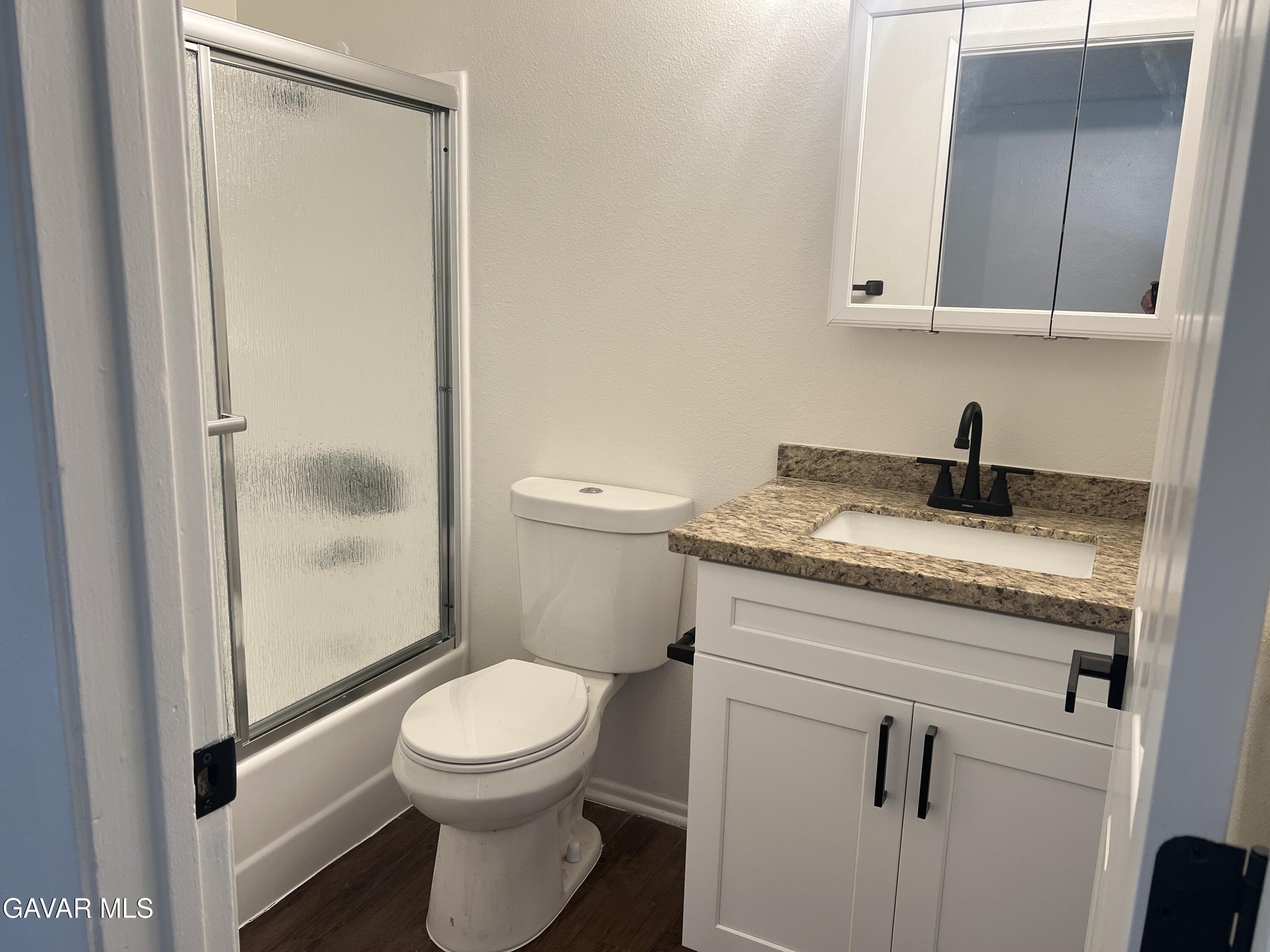 4202 West Ave L, Unit 7 Quartz Hill, CA 93536 - Photo 3 of 14 a bathroom with a granite countertop toilet a sink and a mirror