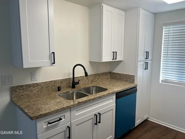 a kitchen with granite countertop white cabinets and a sink