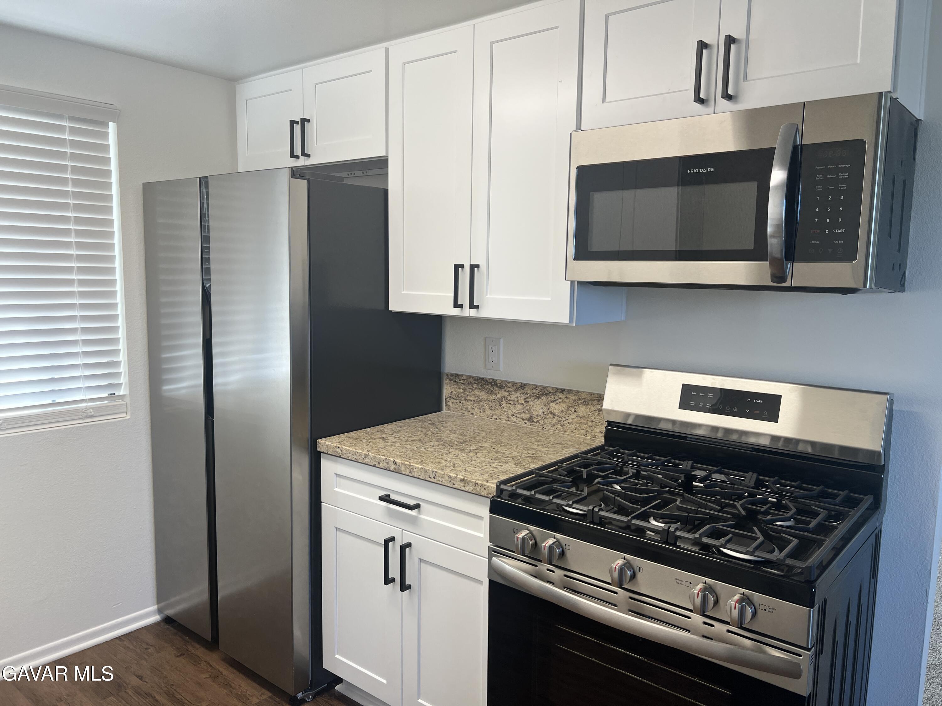 4202 West Ave L, Unit 7 Quartz Hill, CA 93536 - Photo 5 of 14 a kitchen with stainless steel appliances white cabinets and a stove a refrigerator a sink