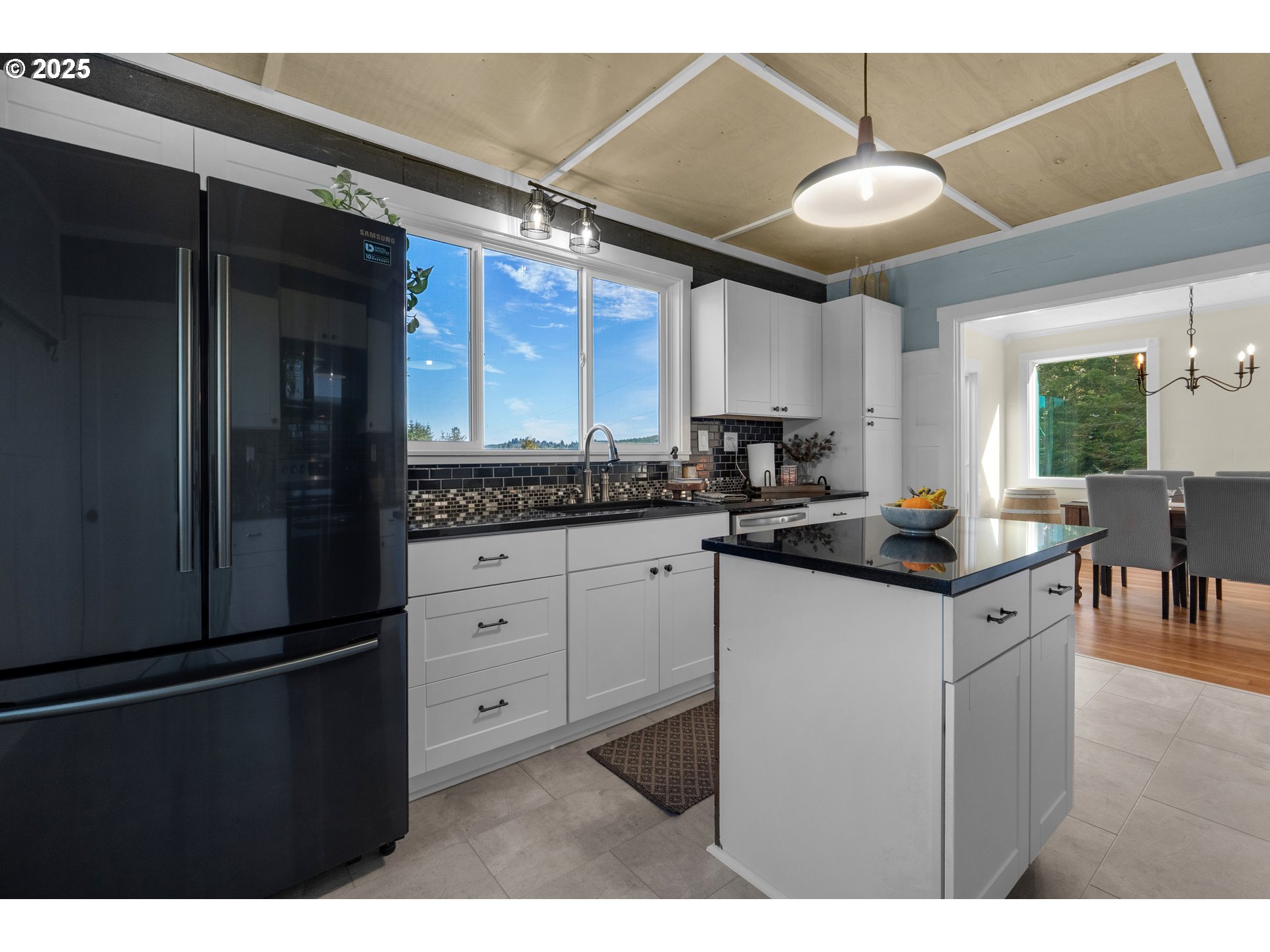 90635 Spring Road Astoria, OR 97103 - Photo 21 of 38 a kitchen with stainless steel appliances kitchen island granite countertop a refrigerator a sink dishwasher a stove and a dining table with wooden floor