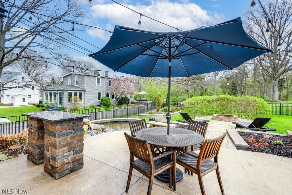 6325 Brecksville Road Independence, OH 44131 - Photo 46 of 50 The property features an expansive patio area with a built-in stone bar, a fire pit area, and a green lawn, surrounded by fenced in yard