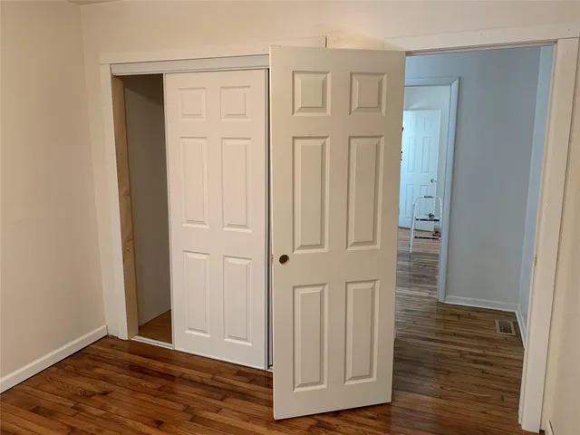 an empty room with wooden floor & closet area