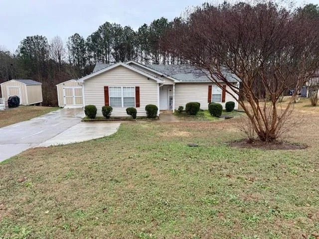 a view of a house with large trees and wooden fence