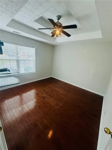 an empty room with wooden floor fan and windows