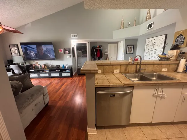 a kitchen with stainless steel appliances granite countertop a sink dishwasher stove and wooden floor