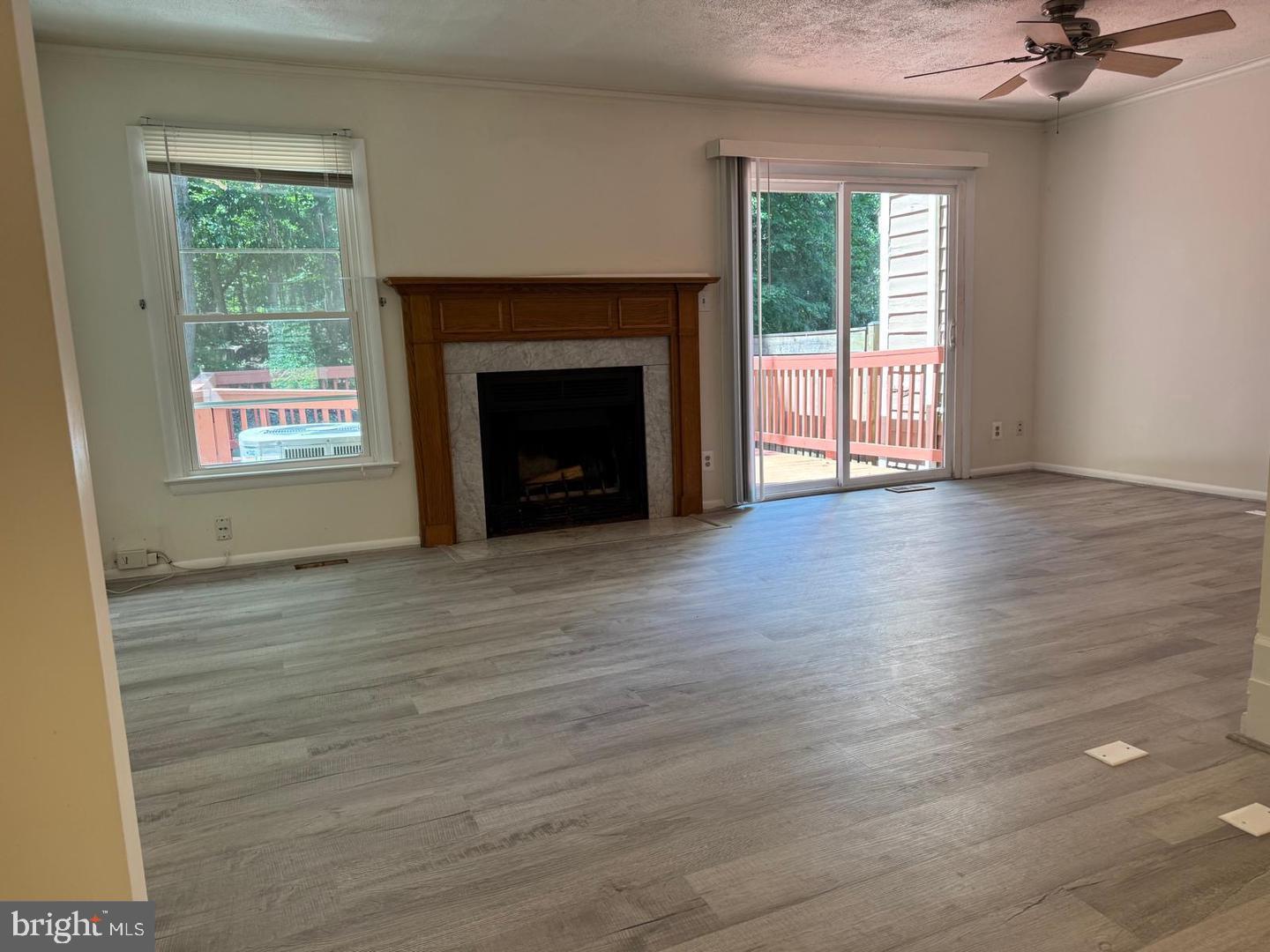 1631 Oak Spring Way Reston, VA 20190 - Photo 2 of 10 an empty room with wooden floor a fireplace and windows
