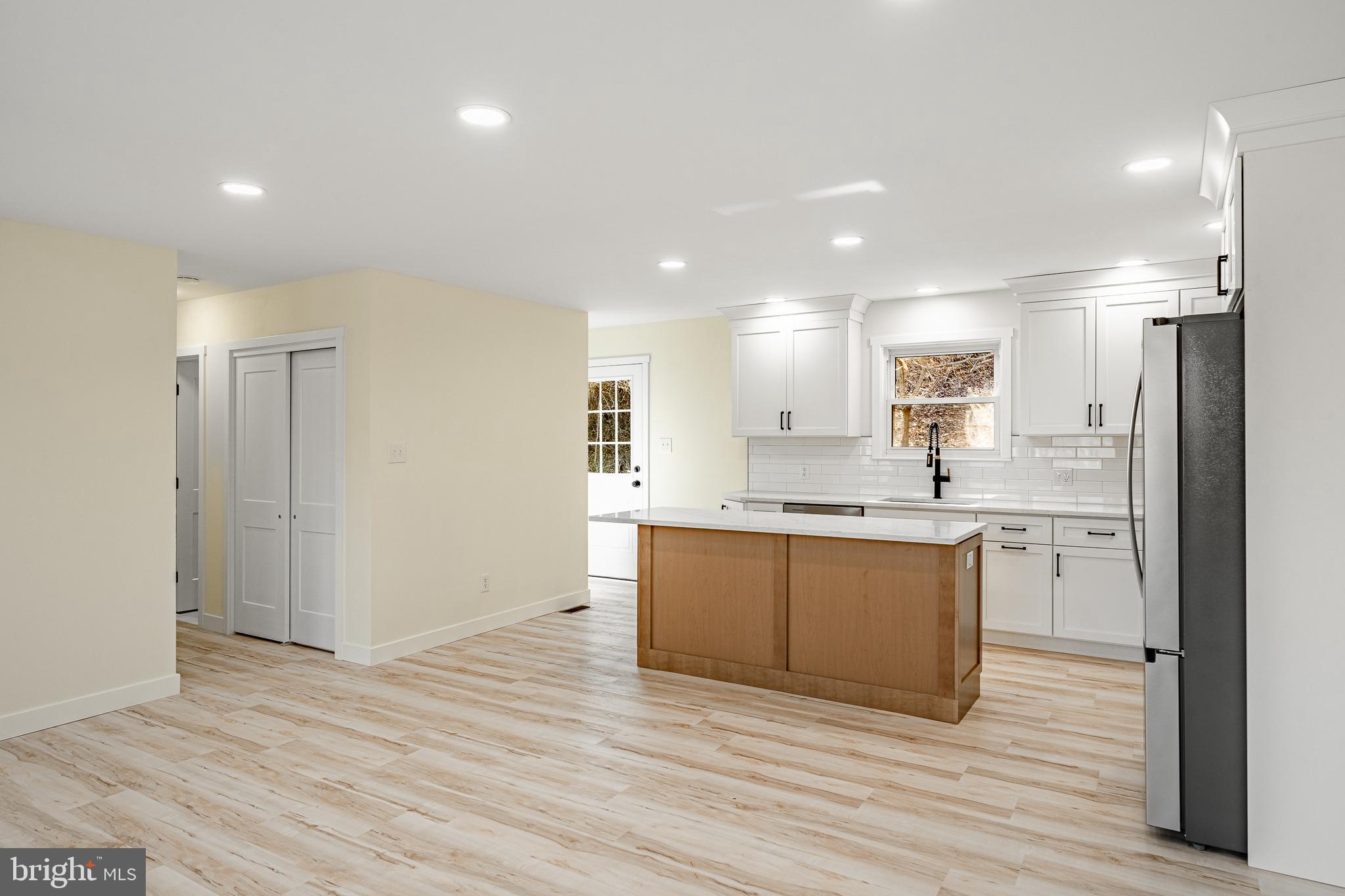 231 Laurel Bridge Road Landenberg, PA 19350 - Photo 11 of 57 a large kitchen with kitchen island a sink dishwasher a refrigerator and white cabinets with wooden floor