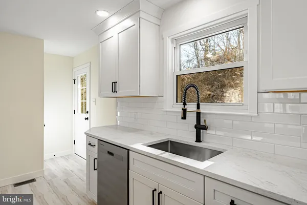 a kitchen with a sink a counter top space stainless steel appliances and cabinets