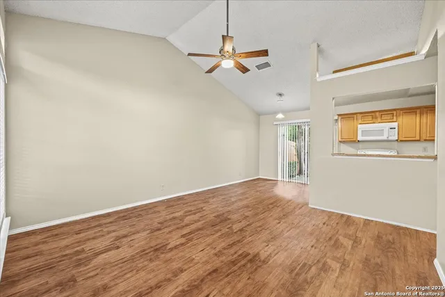 a view of empty room with wooden floor and ceiling fan