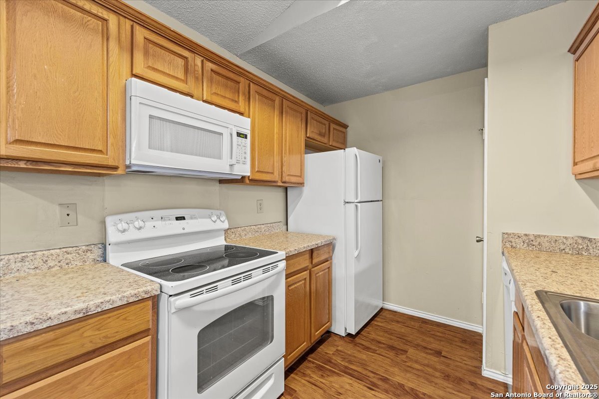 9140 Timber Path, Unit 1403 San Antonio, TX 78250 - Photo 7 of 24 a kitchen with a stove top oven a refrigerator and cabinets