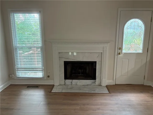 a view of an empty room with wooden floor fireplace and a window
