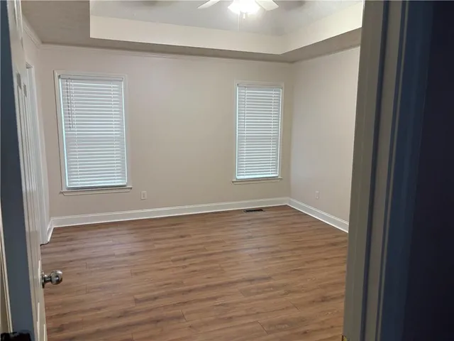 an empty room with wooden floor and windows