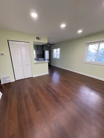 an empty room with wooden floor and windows