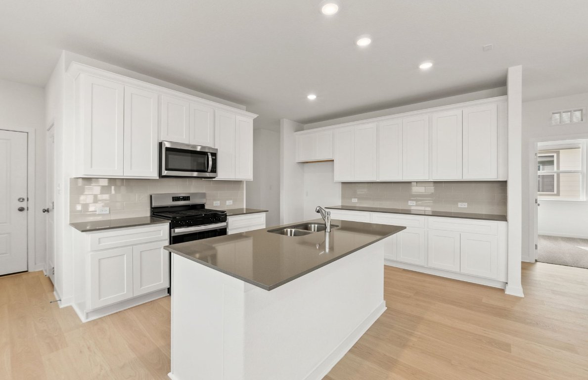 408 Sullivan Way Elgin, TX 78621 - Photo 4 of 22 a kitchen with sink a microwave and cabinets