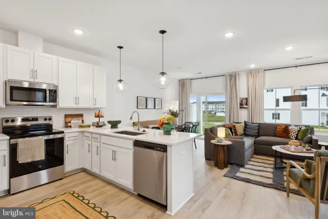 a open kitchen with stainless steel appliances granite countertop a stove top oven a sink dishwasher a dining table and chairs with wooden floor